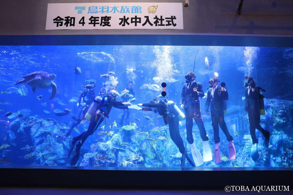 水中で、飼育研究部部長から辞令を受け取る新入社員代表の山路さん